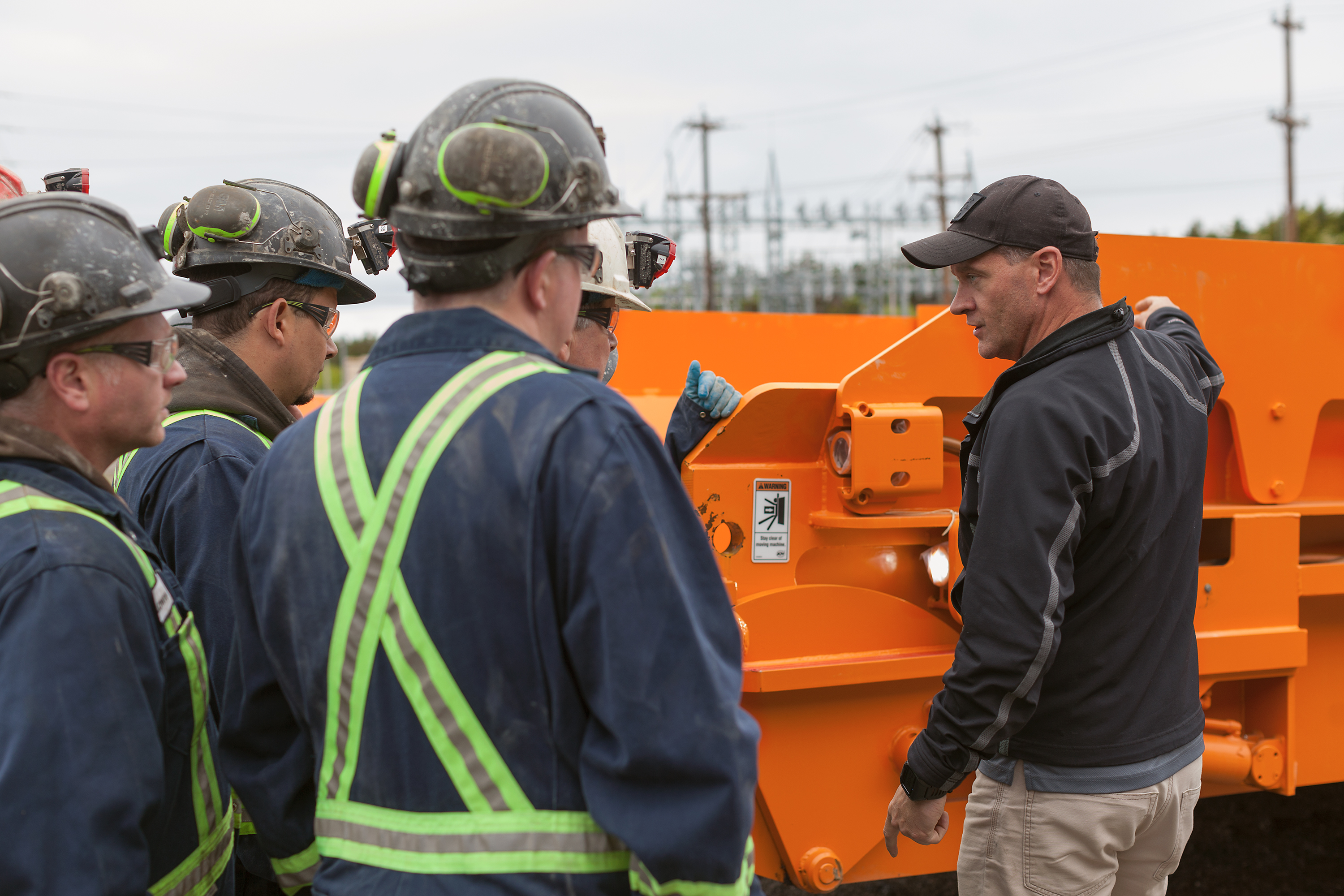 Kendall Messer speaking to surface mining trainees with mining equipment behind the group in Nova Scotia