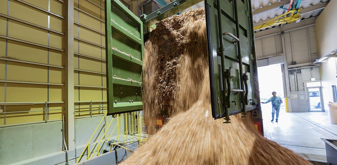 Komatsu employee empties a shipment of woodchips into the burner holding bin