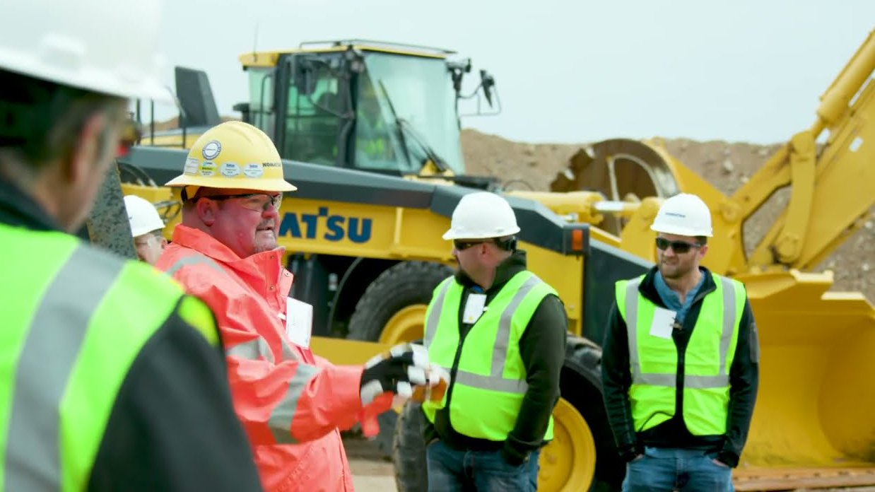 an illustration showing an komatsu excavator with a connecton to an overhead satellite.
