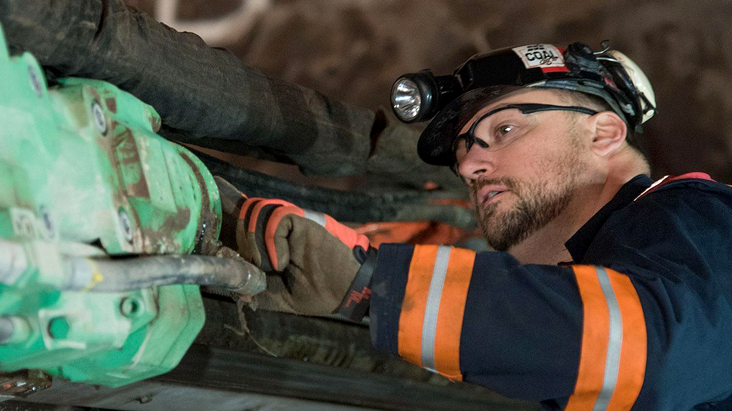 A worker using a Komatsu HC95LC hard rock drifter in an underground mine.